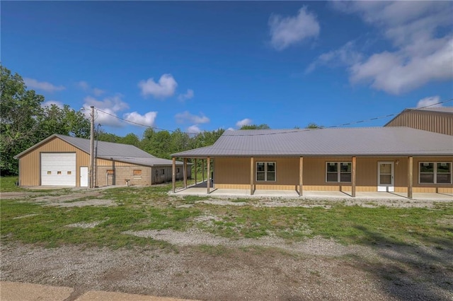 rear view of property featuring a garage, an outdoor structure, and a porch