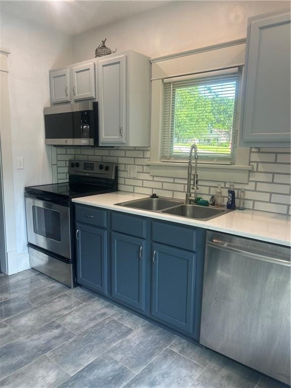 kitchen featuring blue cabinetry, appliances with stainless steel finishes, sink, and tasteful backsplash