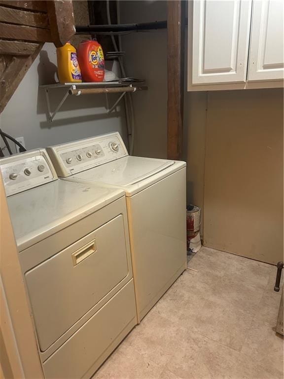 clothes washing area featuring separate washer and dryer and cabinets