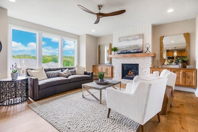 living room with a fireplace, ceiling fan, and light hardwood / wood-style flooring