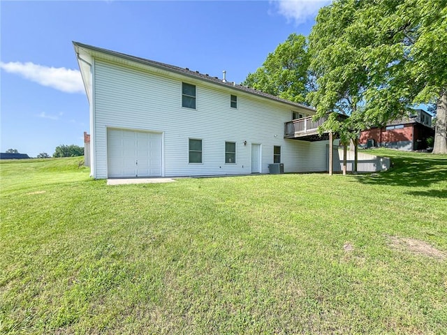 rear view of house with a garage, central AC unit, and a yard