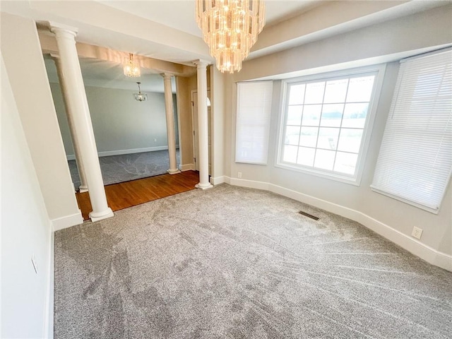 spare room with carpet, a notable chandelier, and decorative columns