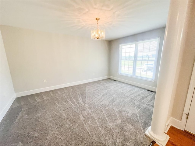 spare room with carpet floors, an inviting chandelier, and ornate columns