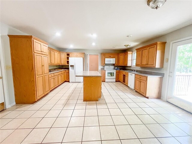 kitchen with a center island, sink, white appliances, and light tile floors