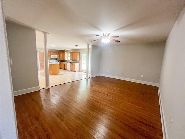 unfurnished living room with ornate columns, ceiling fan, and light wood-type flooring