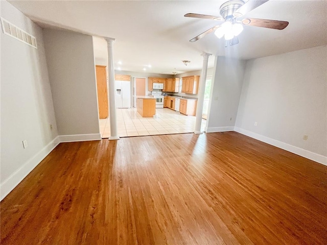 unfurnished living room with ceiling fan, ornate columns, and light tile floors