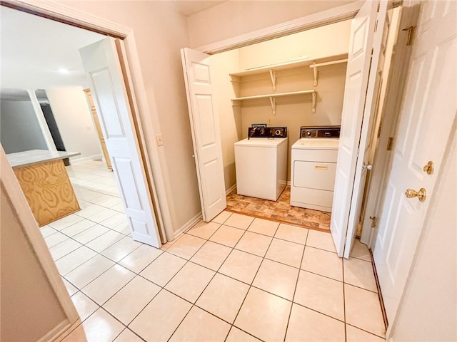 clothes washing area with washer and clothes dryer and light tile floors