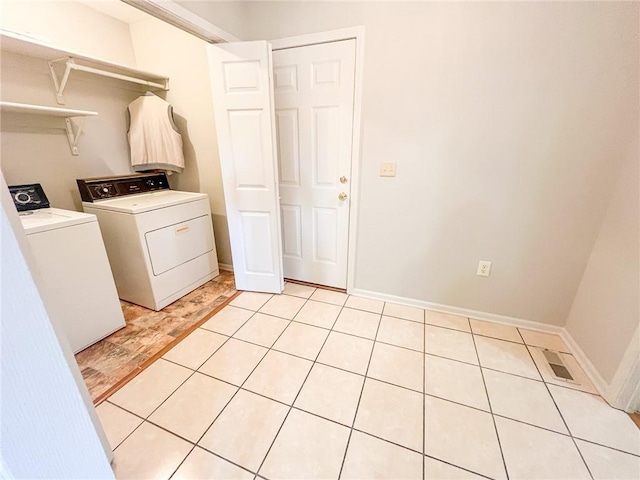 laundry area with independent washer and dryer and light tile floors