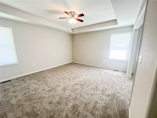 carpeted empty room featuring ceiling fan and a tray ceiling