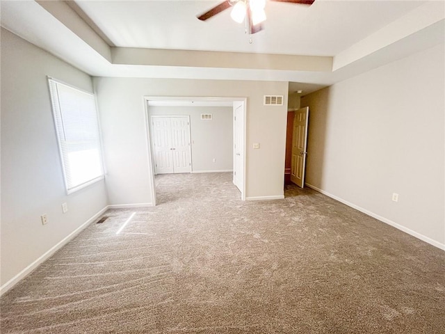 unfurnished bedroom featuring carpet, ceiling fan, and a tray ceiling