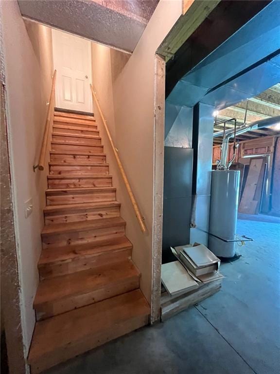 staircase featuring a textured ceiling and gas water heater