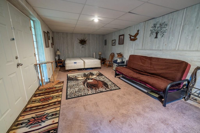 living room with wooden walls, carpet floors, and a paneled ceiling