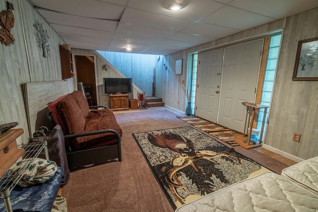 living room featuring wooden walls, carpet flooring, and a paneled ceiling