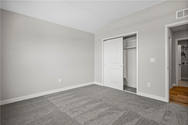 unfurnished bedroom with lofted ceiling, carpet floors, and a closet