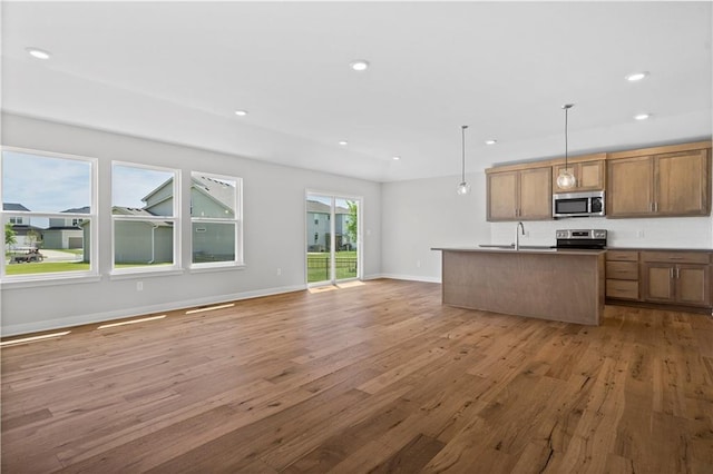 kitchen featuring pendant lighting, sink, hardwood / wood-style flooring, an island with sink, and stainless steel appliances