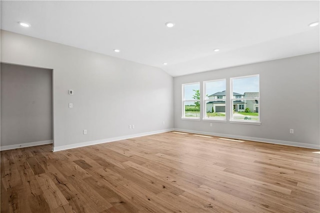 spare room featuring light hardwood / wood-style floors and vaulted ceiling