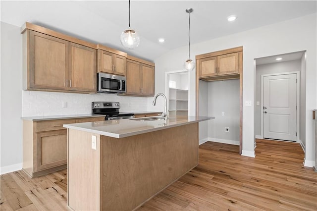 kitchen featuring pendant lighting, a center island with sink, sink, light hardwood / wood-style flooring, and stainless steel appliances