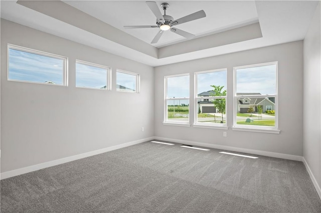 carpeted empty room with a raised ceiling and ceiling fan