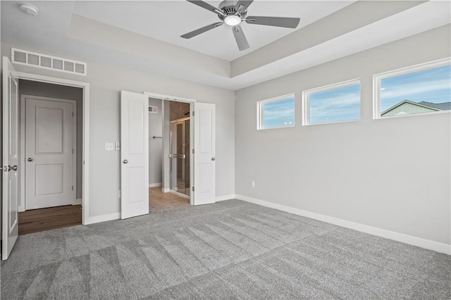 unfurnished bedroom featuring carpet, multiple windows, and ceiling fan