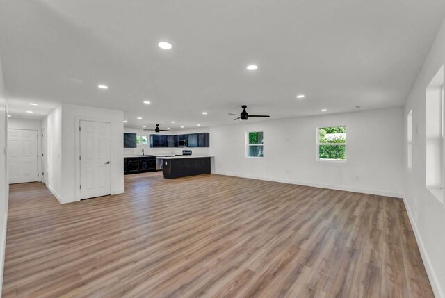 unfurnished living room featuring sink, ceiling fan, and light wood-type flooring