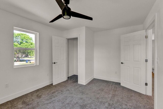 unfurnished bedroom featuring ceiling fan and dark carpet