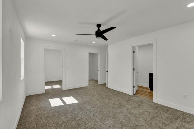 unfurnished bedroom featuring a walk in closet, a closet, carpet, and ceiling fan