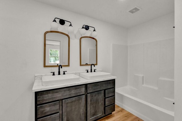 bathroom featuring dual bowl vanity, hardwood / wood-style floors, and shower / bath combination