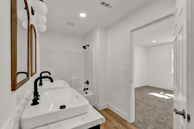 bathroom with washtub / shower combination, vanity, and hardwood / wood-style floors