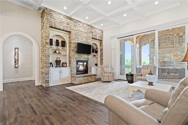 living room with coffered ceiling, dark wood-type flooring, beam ceiling, built in features, and a fireplace