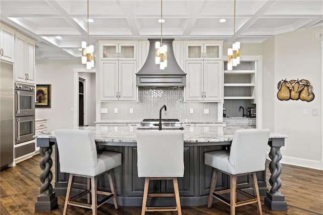 kitchen with premium range hood, an island with sink, and dark hardwood / wood-style floors