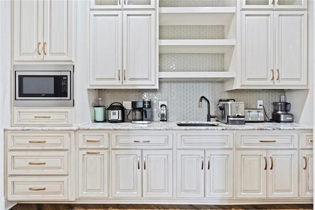 kitchen with light stone counters, stainless steel microwave, and white cabinets