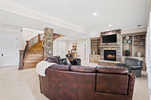 living room featuring built in shelves, a stone fireplace, and ornamental molding