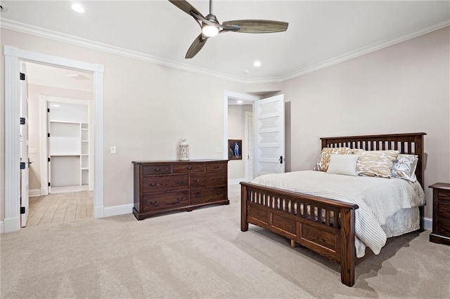 carpeted bedroom with a closet, a spacious closet, ceiling fan, and ornamental molding