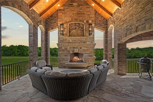 patio terrace at dusk with a grill and an outdoor stone fireplace