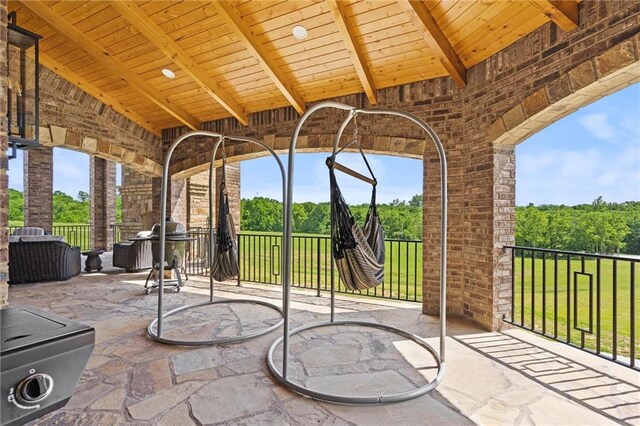 unfurnished sunroom with vaulted ceiling with beams, a wealth of natural light, and wooden ceiling