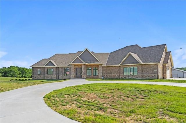 view of front of home featuring brick siding, curved driveway, and a front yard