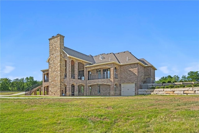 back of property featuring a chimney, stairway, an attached garage, a yard, and brick siding