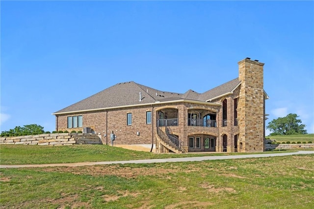 rear view of property with brick siding, a lawn, and a chimney