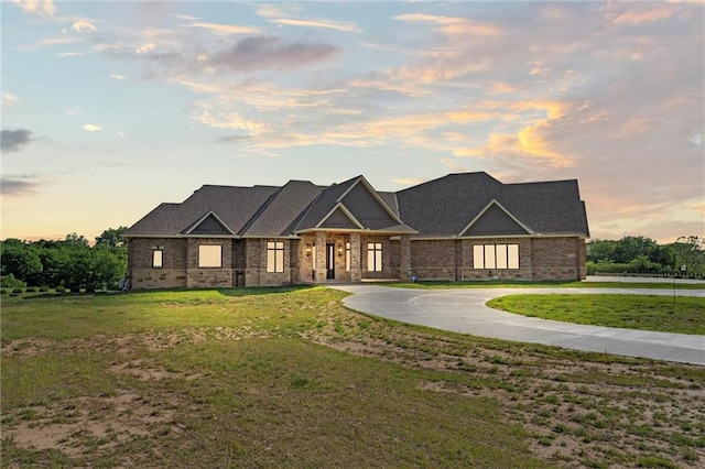 view of front of house featuring driveway, brick siding, and a front yard