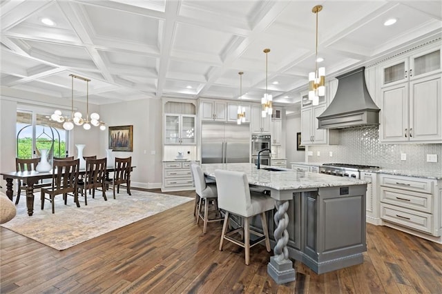 kitchen featuring a large island, custom range hood, and glass insert cabinets