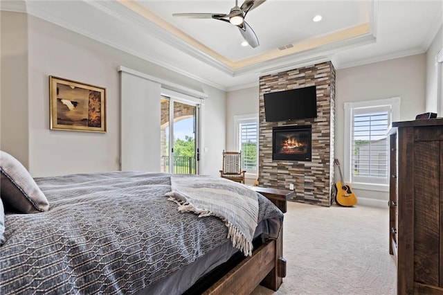 bedroom with access to outside, a raised ceiling, multiple windows, and crown molding