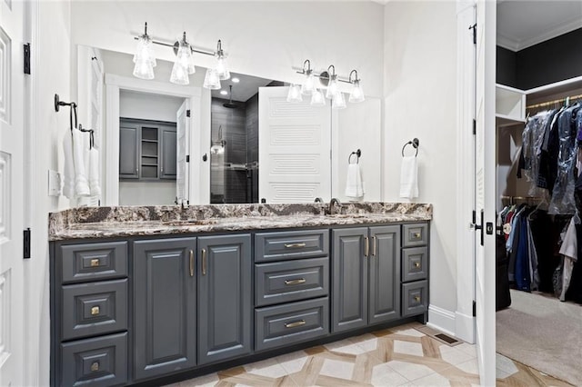 full bathroom with double vanity, a spacious closet, a sink, a shower stall, and baseboards