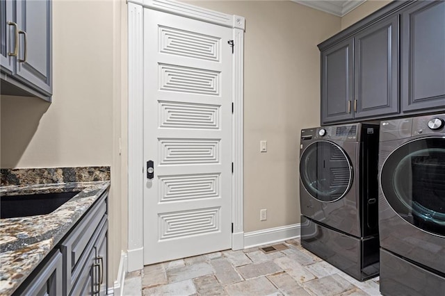 laundry room with washing machine and dryer, stone tile floors, baseboards, ornamental molding, and cabinet space