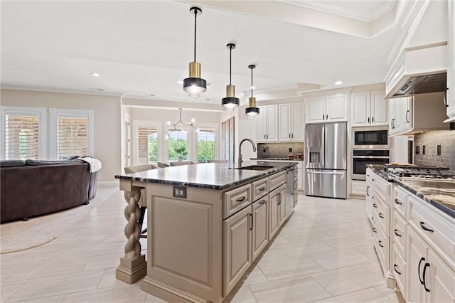 kitchen featuring a center island with sink, stainless steel appliances, hanging light fixtures, open floor plan, and a sink