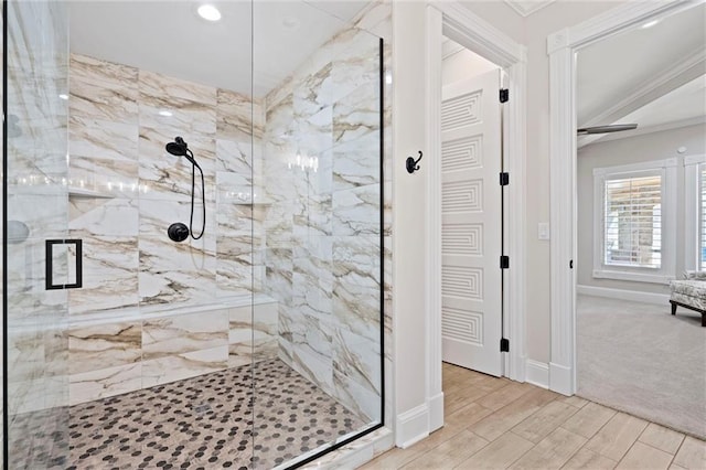 bathroom featuring wood tiled floor, a marble finish shower, baseboards, and ornamental molding