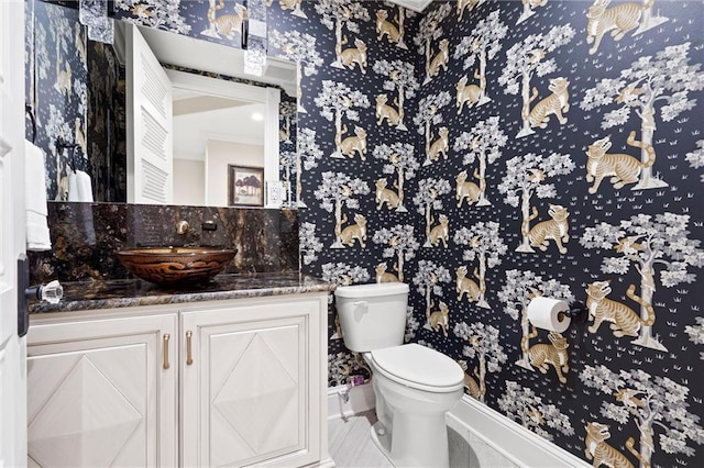 bathroom with vanity, toilet, and wallpapered walls