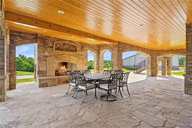 view of patio with stairs, outdoor dining space, and an outdoor stone fireplace