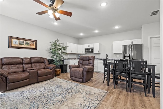 living room featuring light wood-style floors, recessed lighting, visible vents, and ceiling fan