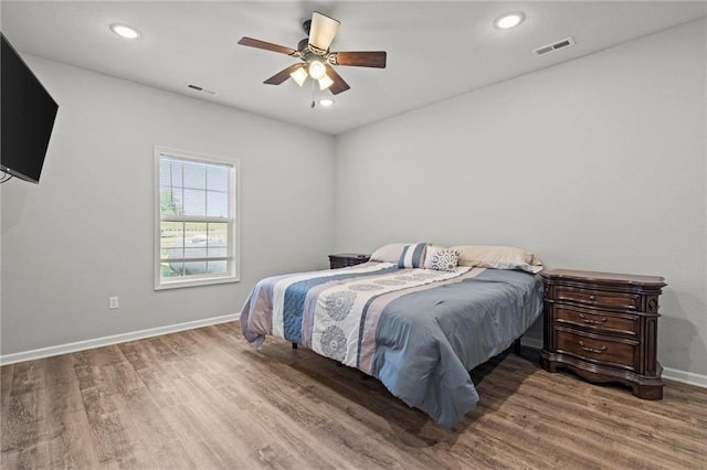 bedroom with baseboards, visible vents, and wood finished floors