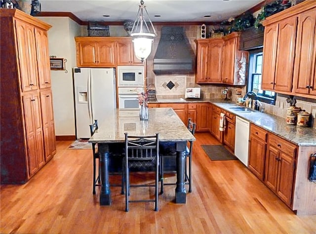 kitchen with light hardwood / wood-style floors, crown molding, white appliances, custom range hood, and a kitchen island